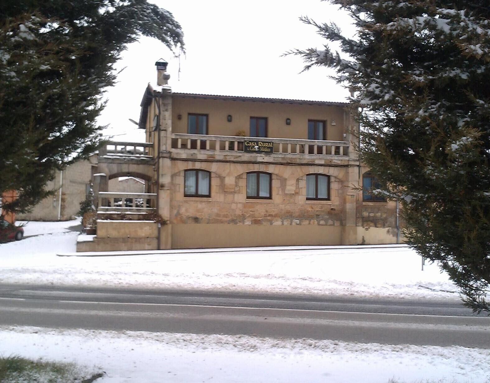 A two-story building with a balcony, a sign reading 'Casa Rural,' and a snow-covered ground.