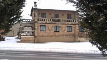 A two-story building with a balcony, a sign reading 'Casa Rural,' and a snow-covered ground.