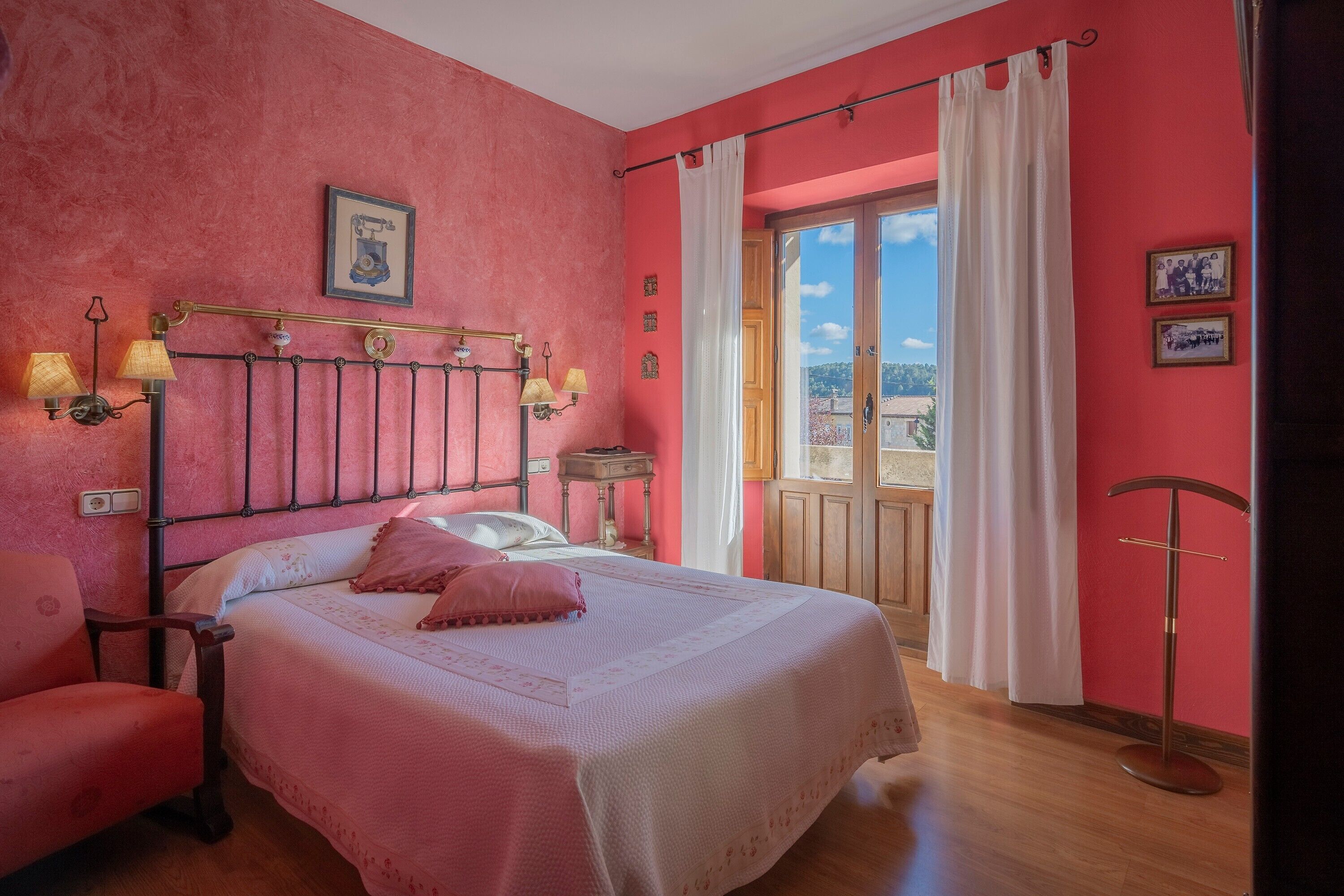 Una habitación con cama, una silla, una mesita de noche, una lámpara y vistas al exterior.