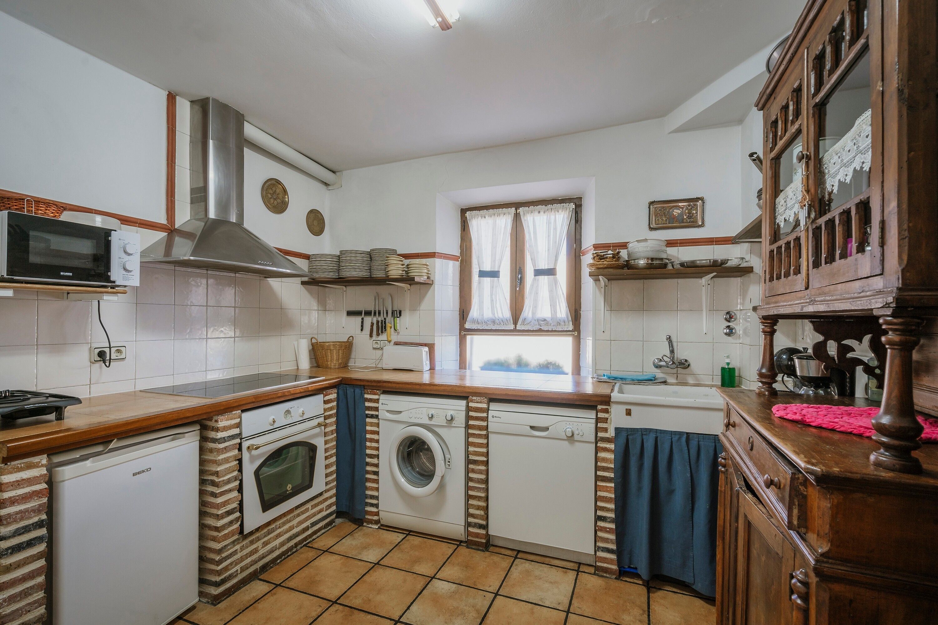 Una cocina equipada con microondas, estufa, horno, lavadora y lavavajillas.