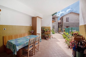 Un espace patio aménagé avec une table et des chaises, des plantes en pot et une vue sur un bâtiment en cours de rénovation, avec des échafaudages.