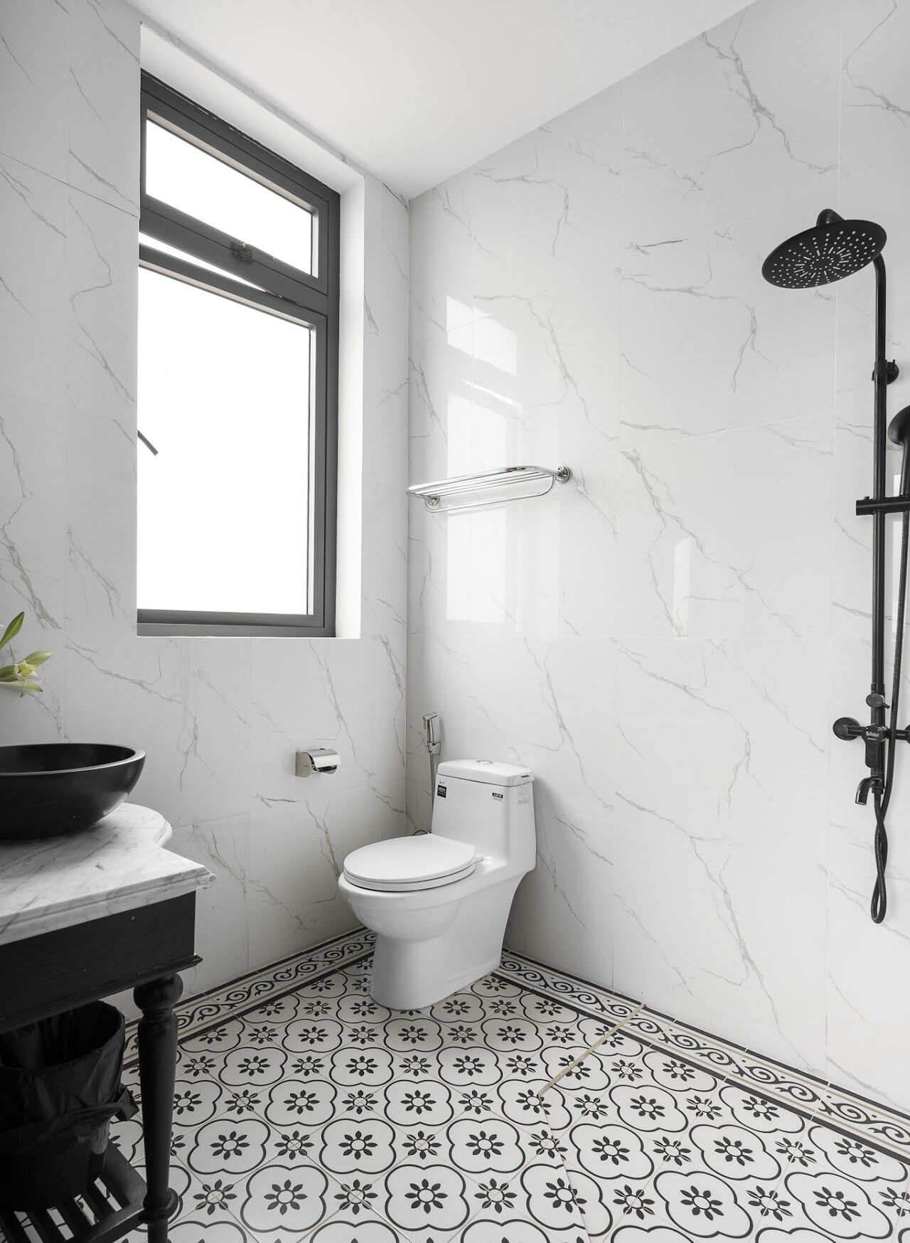 A bathroom with a toilet, a shower, a sink with a bowl, and a window.