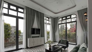 A spacious living room with a large TV, comfortable seating, and a patterned floor. - The Gate Boutique Hotel Da Lat (Xuan Huong - Da Lat)