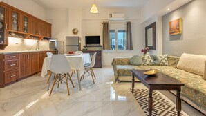 A modern living room with a sofa, dining table, and kitchen area.