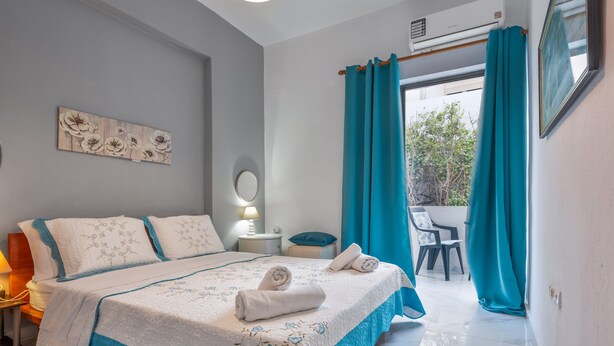A bedroom with a bed, a bedside table, a lamp, a window with curtains, and a view of the outside.