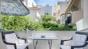A balcony with two chairs, a table, and a patterned umbrella.