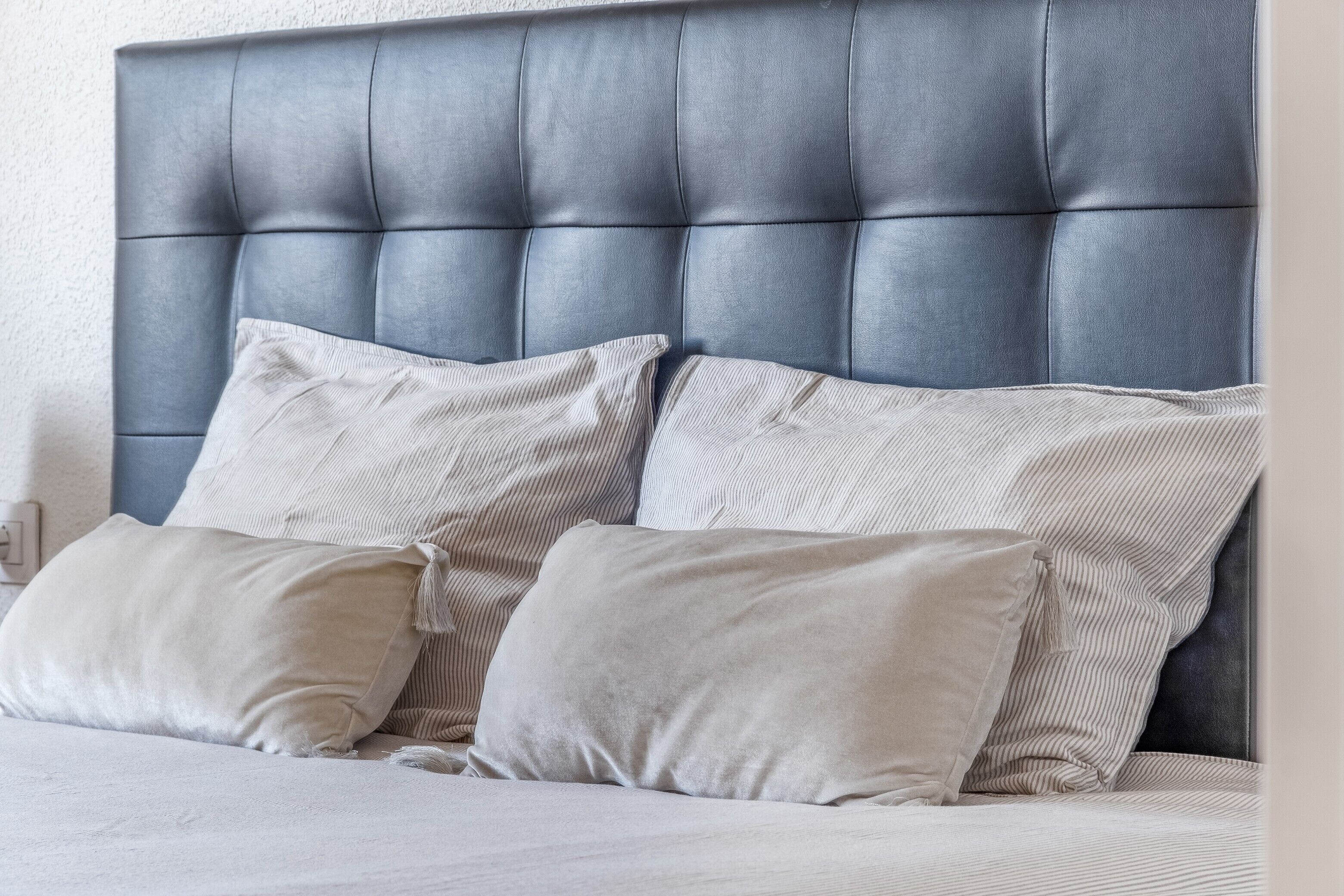 A bed with a tufted headboard, two pillows, and a plain wall.