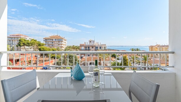 A balcony with a table, chairs, and a decorative blue vase. - Apartment 'Beach Front Sea View Punta Prima' with Sea View, Wi-Fi and Air Conditioning (Torrevieja)