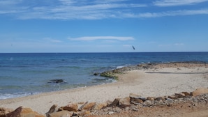 A beach with clear skies, calm water, and rocky shoreline. - Apartment 'Beach Front Sea View Punta Prima' with Sea View, Wi-Fi and Air Conditioning (Torrevieja)