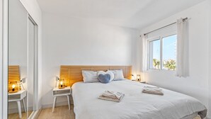 A bedroom with a bed, bedside tables, a mirror, and a window. - Apartment 'Beach Front Sea View Punta Prima' with Sea View, Wi-Fi and Air Conditioning (Torrevieja)