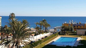 A coastal hotel with a swimming pool, palm trees, and a view of the sea. - Apartment 'Beach Front Sea View Punta Prima' with Sea View, Wi-Fi and Air Conditioning (Torrevieja)