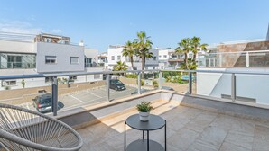Een balkon met een stoel, een tafeltje en een bloempot.