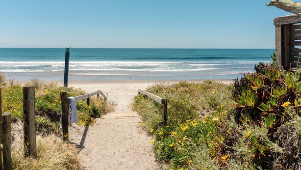 A sandy beach path leading to the ocean with wooden railings and a wooden structure on the right. - Sleeps 4, Estuary Front in Pukehina Beach, two minutes to beach (Pukehina)