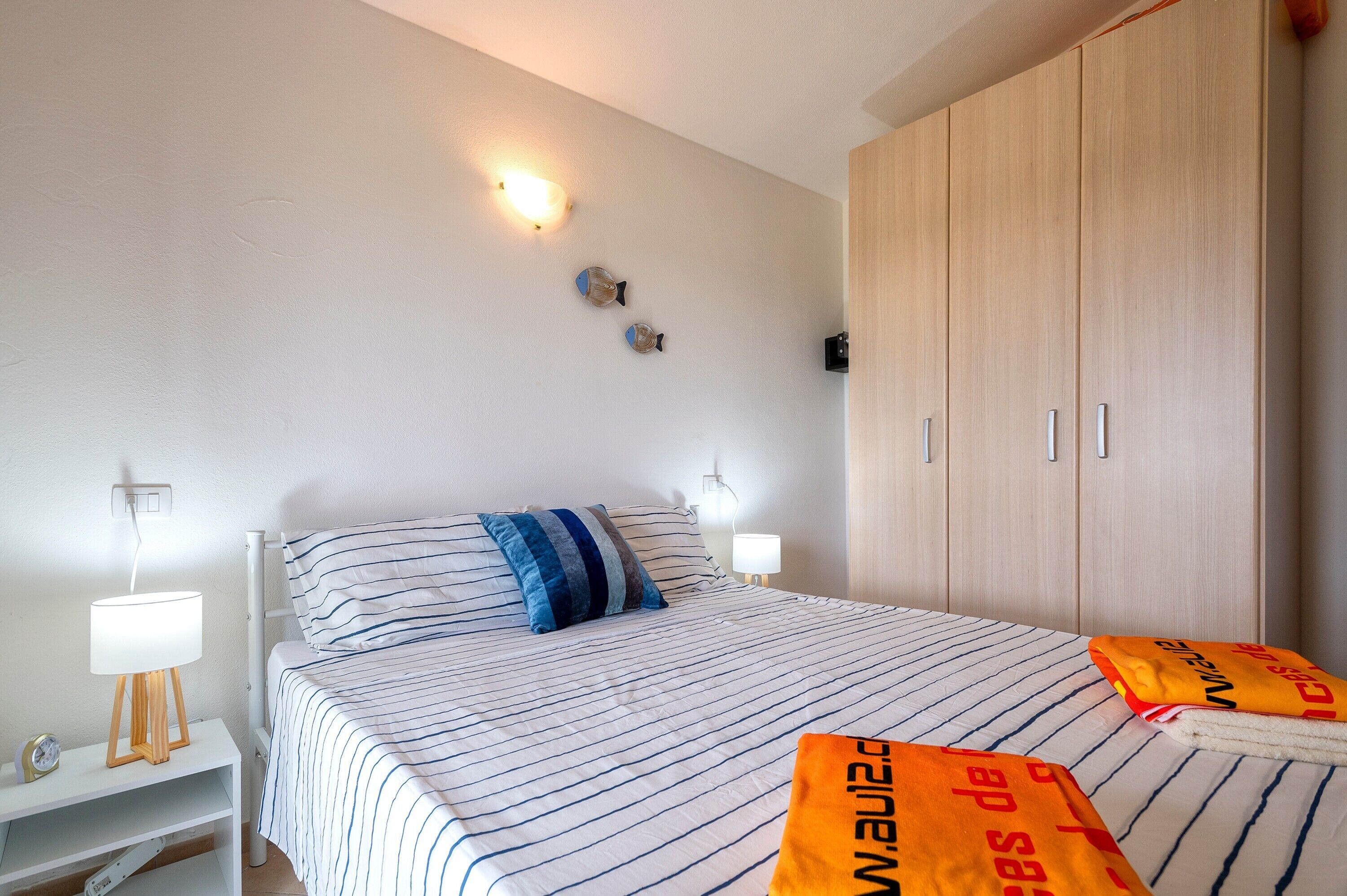 A hotel room with a bed, bedside lamps, a nightstand, and a wardrobe.