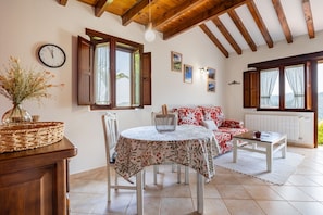 Una habitación acogedora con una mesa de comedor, un sofá y una ventana con cortinas.