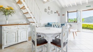 A kitchen with a white staircase, a dining table with chairs, a view of the outdoors, and a sign reading 'SALIDA'.