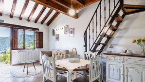 Un comedor con mesa y sillas, una escalera y vistas al exterior.