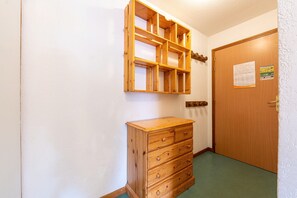 Une pièce comprenant une commode en bois, une étagère en bois et une porte sur laquelle est affiché un avis.