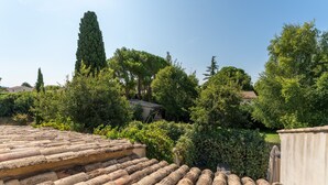 A rooftop terrace with terracotta tiles, surrounded by lush greenery and tall trees. - Holiday Home 'Grand Gîte De Tante Berthe' with Mountain View, Shared Pool and Wi-Fi (Camaret-sur-Aigues)