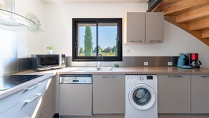 A modern kitchen with a dishwasher, washing machine, microwave, and a window with a view of trees. - Holiday Home 'Grand Gîte De Tante Berthe' with Mountain View, Shared Pool and Wi-Fi (Camaret-sur-Aigues)