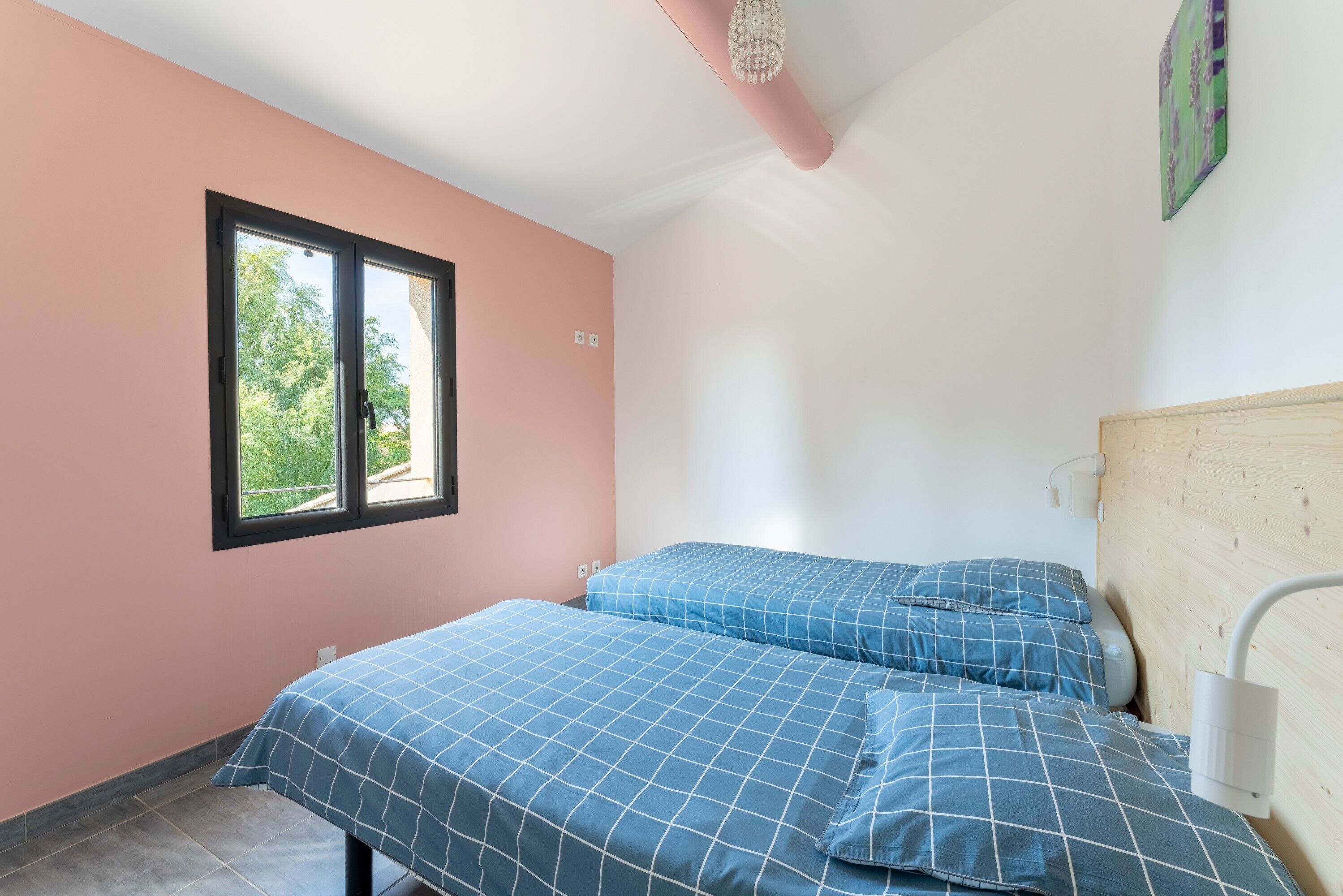 Ein Schlafzimmer mit zwei Betten, einem Fenster, einem Deckenventilator und einer Wandleuchte.
