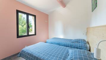 Ein Schlafzimmer mit zwei Betten, einem Fenster, einem Deckenventilator und einer Wandleuchte.