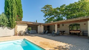 A swimming pool with lounge chairs and a foosball table in a covered outdoor area. - Holiday Home 'Grand Gîte De Tante Berthe' with Mountain View, Shared Pool and Wi-Fi (Camaret-sur-Aigues)