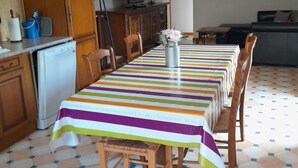 A dining area with a striped tablecloth, wooden chairs, a small refrigerator, and a television on a cabinet. - Apartment 'La Fontaine Bénite' with Private Terrace, Wi-Fi and Air Conditioning (SEYSSEL)