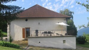 A house with a tiled roof, a balcony with outdoor furniture, and a small garden area. - Apartment 'La Fontaine Bénite' with Private Terrace, Wi-Fi and Air Conditioning (SEYSSEL)