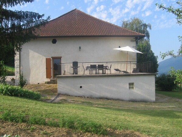 Een huis met een pannendak, een balkon met tuinmeubilair en een kleine tuin.