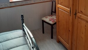A bedroom with a bed, a wooden wardrobe, a chair, and a window with a view of the countryside. - Apartment 'La Fontaine Bénite' with Private Terrace, Wi-Fi and Air Conditioning (SEYSSEL)