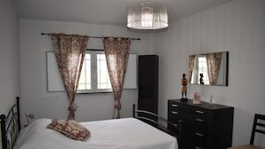 A bedroom with a bed, a dresser, a chair, a mirror, and a chandelier. - Casa Trincadeira – Retreat with Private Jacuzzi Among Vineyards and Views of Palmela Castle (Palmela)