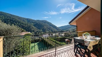 Un balcon avec une table dressée pour le dîner, offrant une vue sur un paysage montagneux.