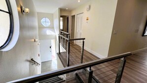 A modern interior with a staircase, a round window, and a door leading to another room.