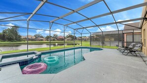 A covered outdoor swimming pool with a view of a lake and houses in the background. - Stunning Newly Renovated Pool Home close to Disney (Davenport)