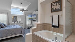 A bedroom with a bed, a vanity, a bathtub, and a ceiling fan. - Wonderful Weston Hills Villa SE Facing Pool (Clermont)