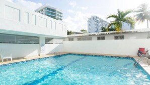 Una piscina con agua cristalina azul, rodeada de paredes blancas y algunas palmeras.