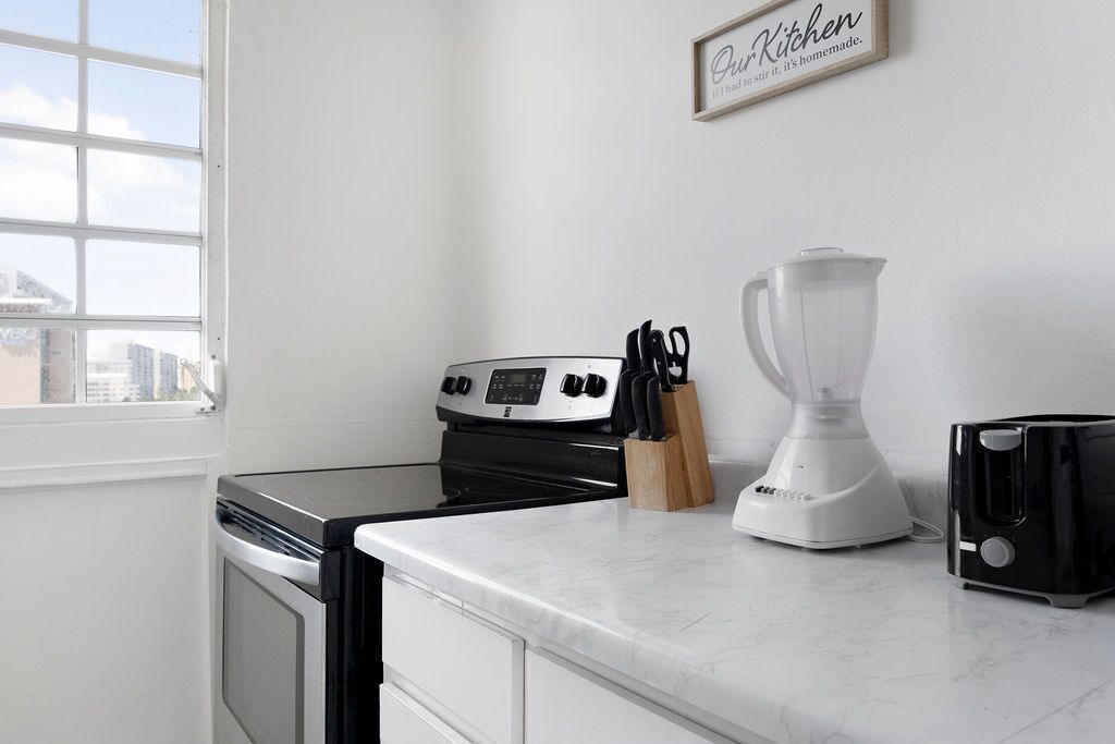 A kitchen with a stove, a blender, and a toaster on the counter.
