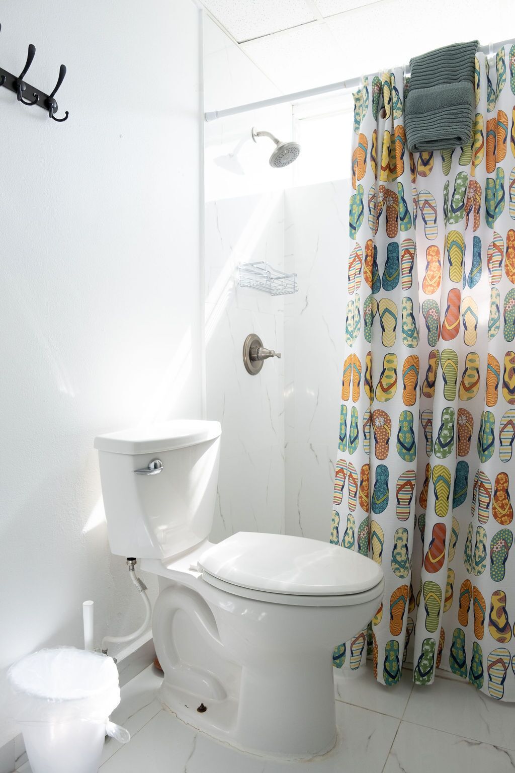 Ein Badezimmer mit Toilette, Dusche und einer Duschvorhang mit Flip-Flop-Muster.