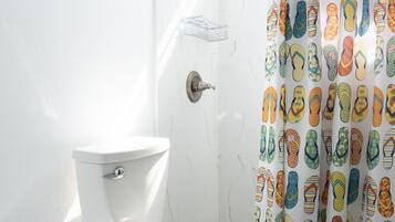 Ein Badezimmer mit Toilette, Dusche und einer Duschvorhang mit Flip-Flop-Muster.