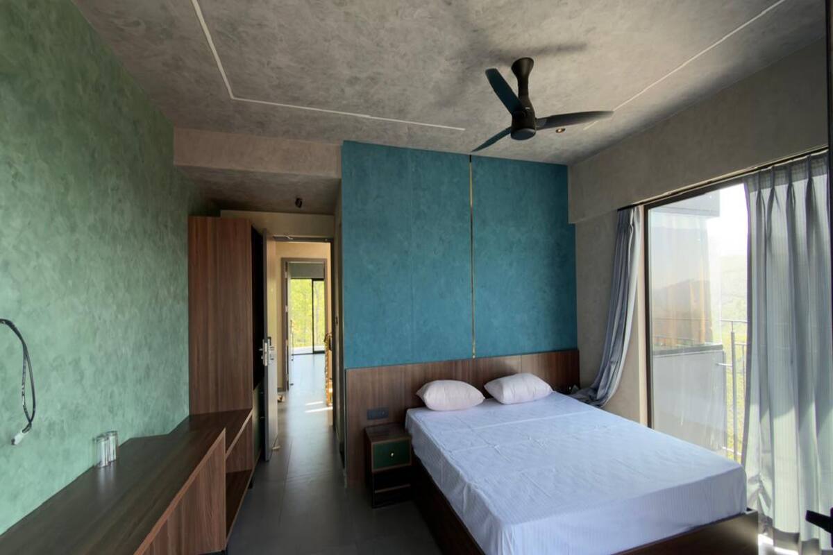 A modern hotel room with a large bed, a ceiling fan, and a view of the outdoors.