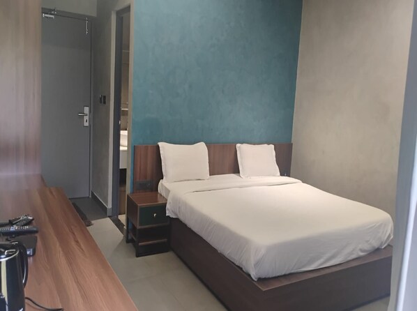 Ein modernes Hotelzimmer mit einem großen Bett, einem Holztisch und einem kleinen Nachttisch.