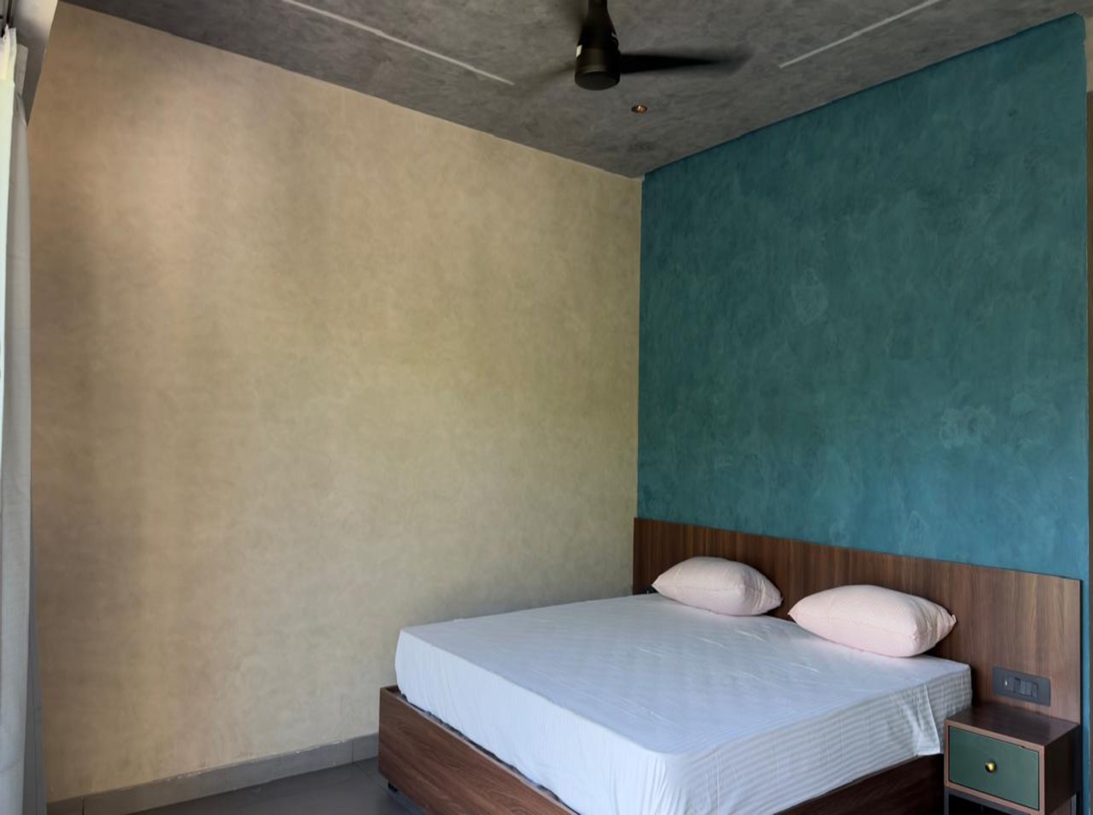 Un dormitorio con cama, mesita de noche y ventilador de techo.