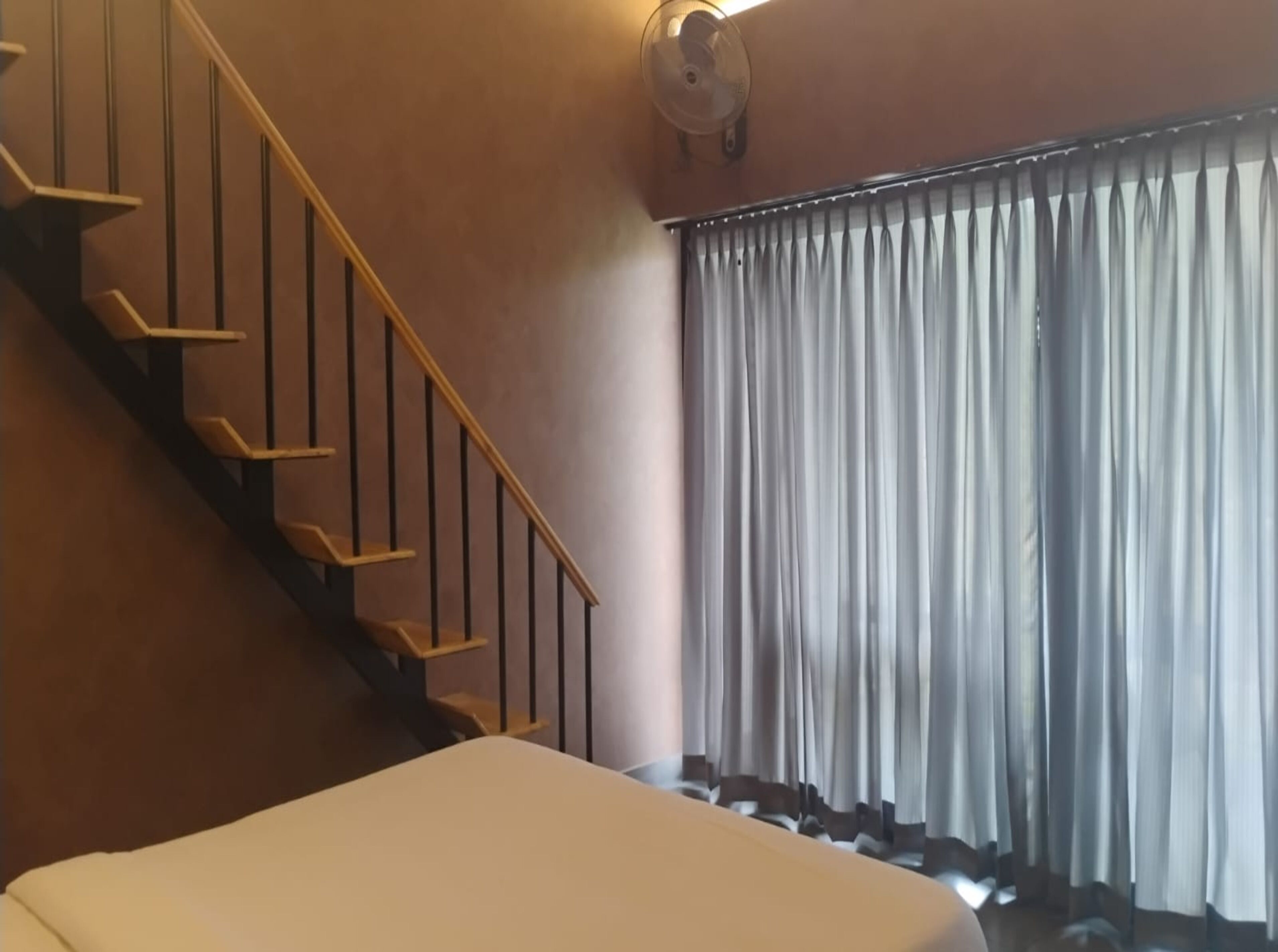 Una camera da letto con un letto, una scala e una finestra con tende.