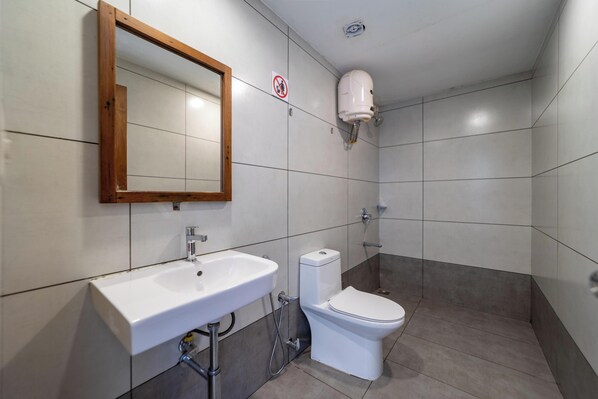 Une salle de bain avec un lavabo blanc, des toilettes et un miroir.