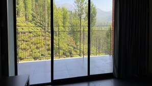 A room with a large sliding glass door leading to a balcony with a metal railing.