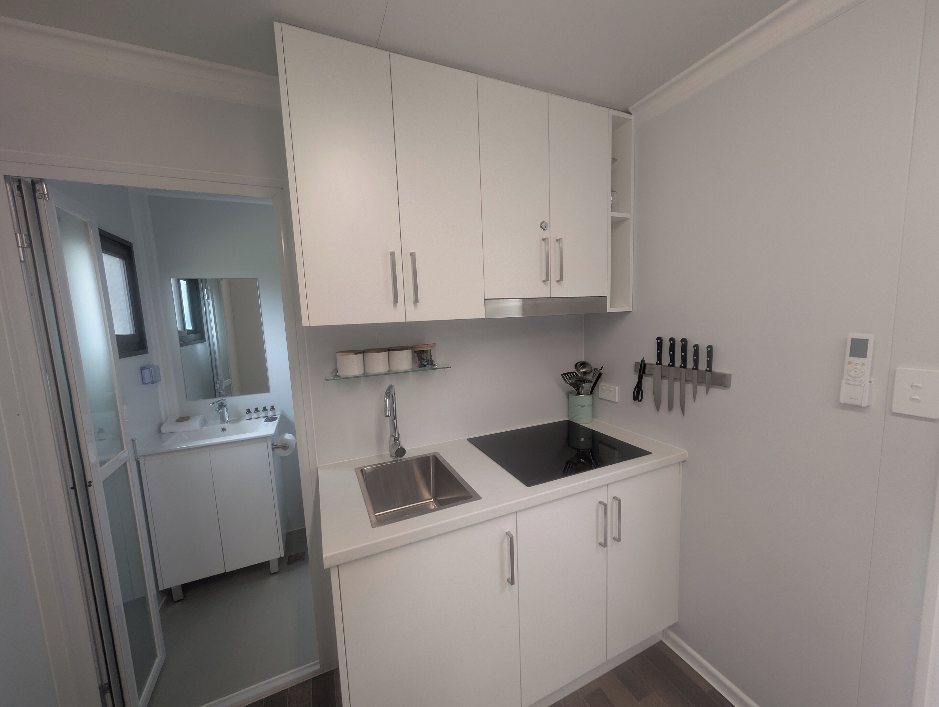 A modern kitchen with white cabinets, a stainless steel sink, and a built-in oven.