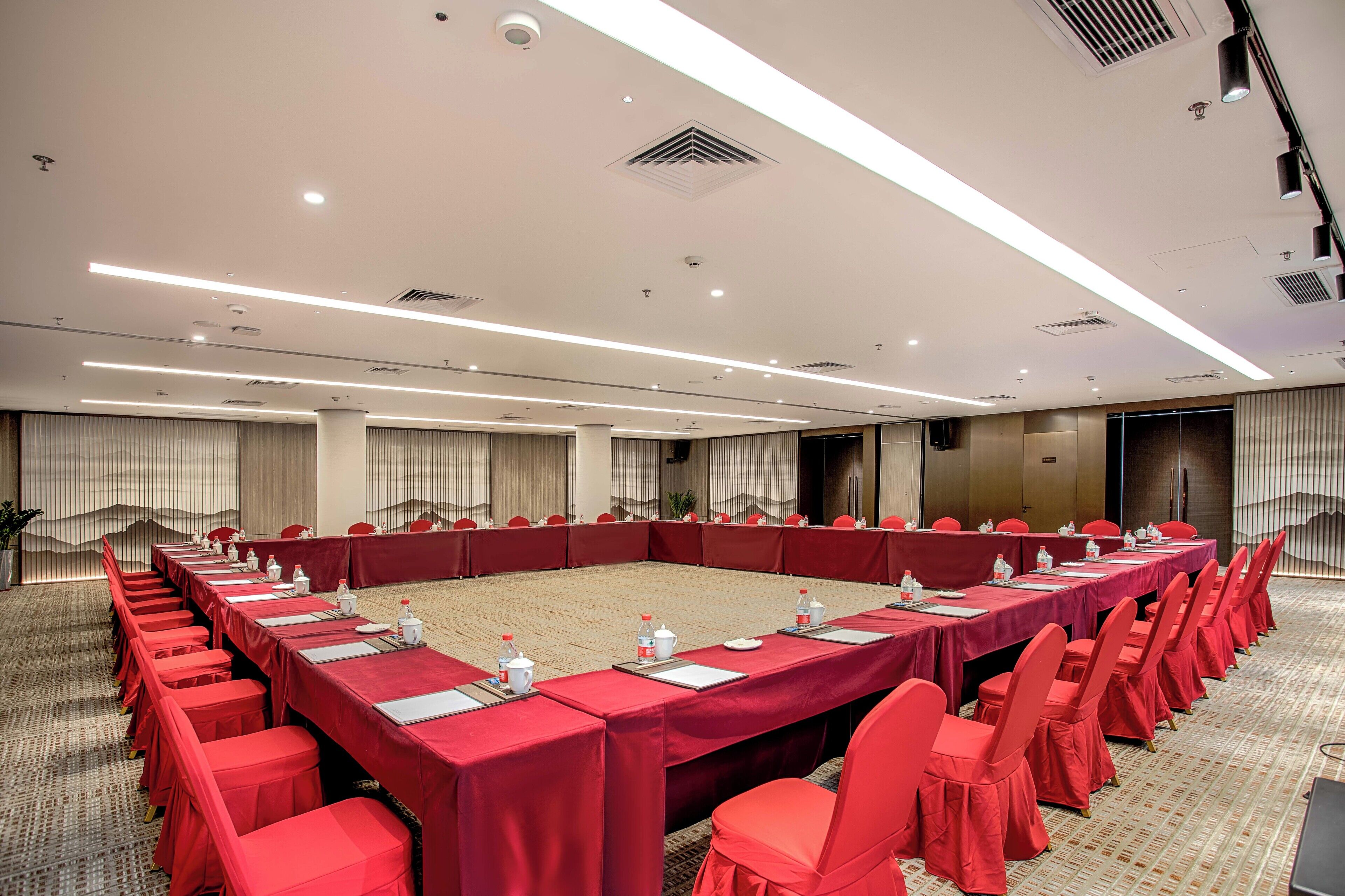 A conference room with a long table, red chairs, and a carpeted floor.