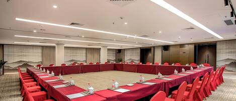 A conference room with a long table, red chairs, and a carpeted floor.