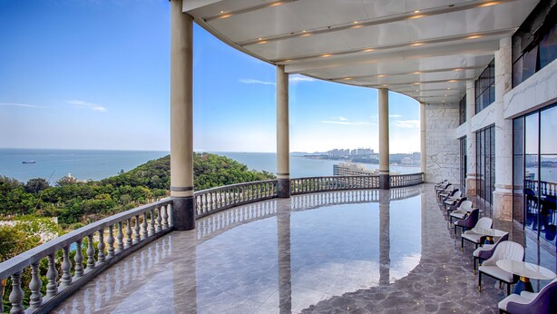 Varanda ampla com guarda-corpo curvo, com vista para o mar e a paisagem urbana.